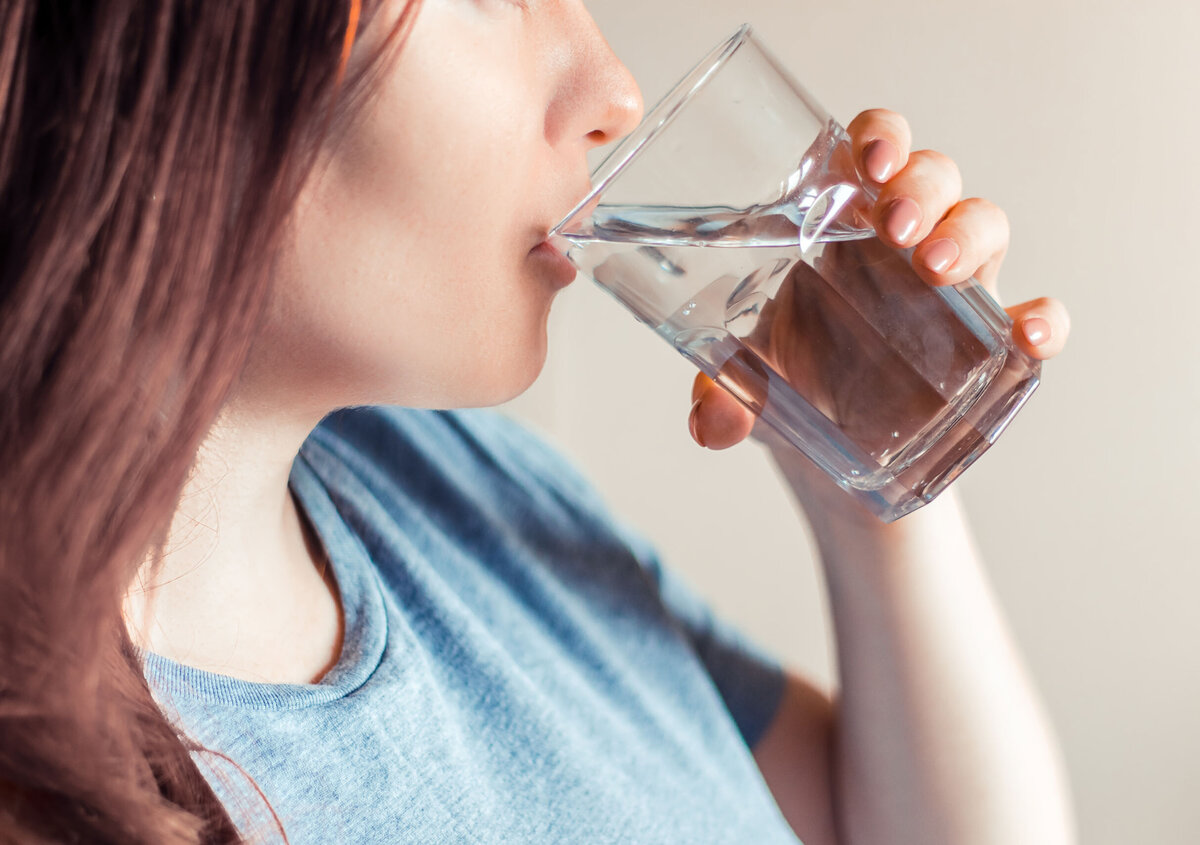 Close-up van een persoon die een glas water drinkt. De afbeelding symboliseert schoon drinkwater, waterkwaliteit en duurzaam waterbeheer.