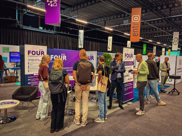Bild vergr&ouml;&szlig;ern: Bezoekers verzamelen zich bij de SmartDocuments-stand op CorporatiePlein 2026 en voeren gesprekken over het documentplatform FOUR.