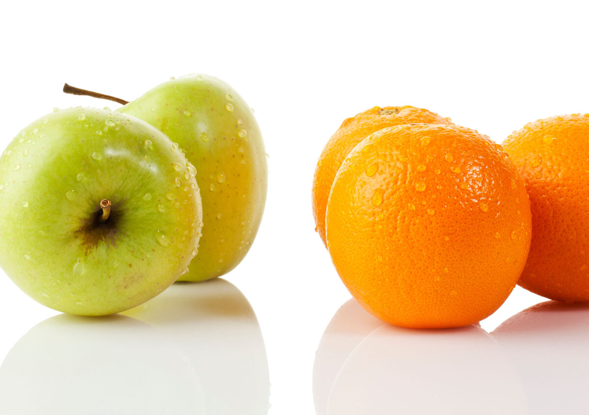 A red apple and a green pear with water droplets are positioned side by side against a light gray background. Both pieces of fruit are shown isolated on the background and each features a stem with a green leaf. The image illustrates the comparison of different objects and serves as a symbolic representation of identifying differences.