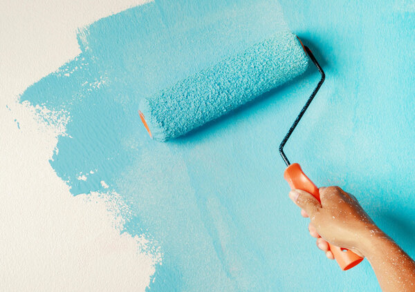 Nahaufnahme einer Farbrolle mit orangem Griff, die eine wei&szlig;e Wand mit hellt&uuml;rkiser Farbe streicht. Die frische Farbschicht bedeckt einen gro&szlig;en Teil der Oberfl&auml;che und erzeugt einen deutlichen Kontrast zwischen dem bereits gestrichenen und dem noch wei&szlig;en Bereich. Das Motiv symbolisiert Gestaltungsspielraum, Individualisierung und die M&ouml;glichkeit, ein Erscheinungsbild nach eigenen Vorstellungen anzupassen.